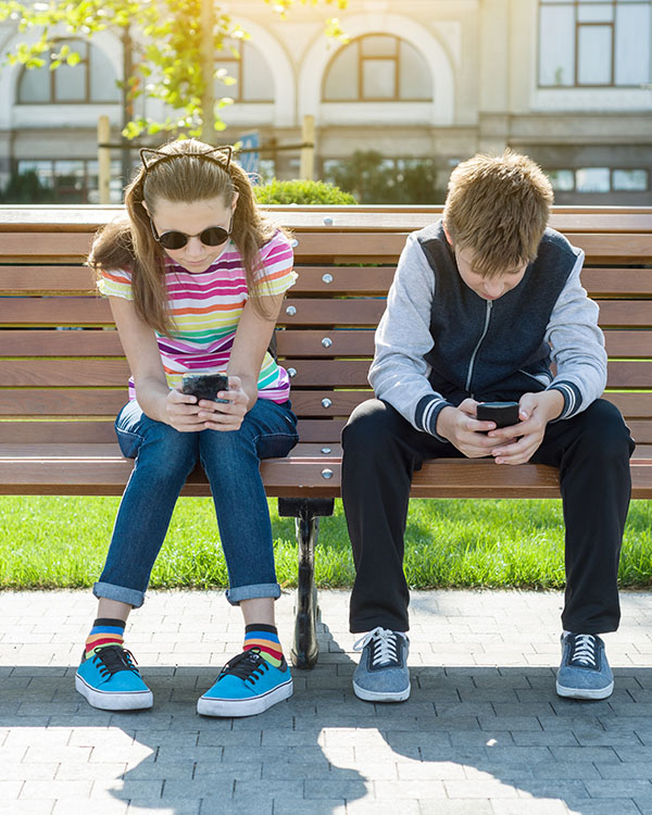 Boy and girl teenagers play, read, look at the smartphone. text neck - tech neck - either way it hurts